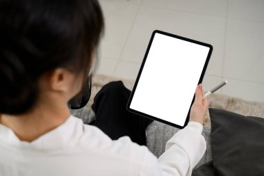 Genç bayan serbest çalışanın kahve içip evde dijital tablet kullanmasına yakın..