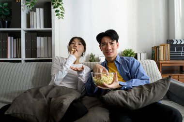 Mutlu genç çift evde film izlerken patlamış mısırın tadını çıkarıyor..