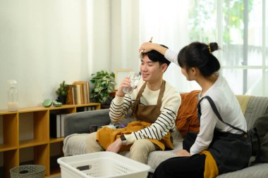 Birlikte temizlik yaptıktan sonra ara veren mutlu genç çift. Ev bakımı ve günlük ev işleri kavramı.