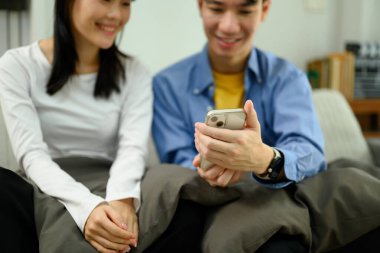 Neşeli genç çift birlikte akıllı telefondan bir şey izliyor..