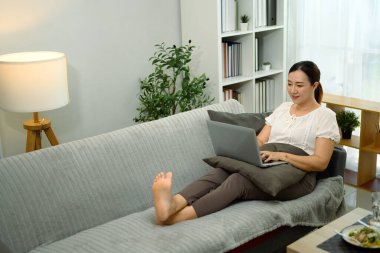 Evde dizüstü bilgisayarda çalışan rahat yetişkin bir kadın..