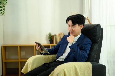 Koltukta dijital tablet kullanan memnun genç girişimci.