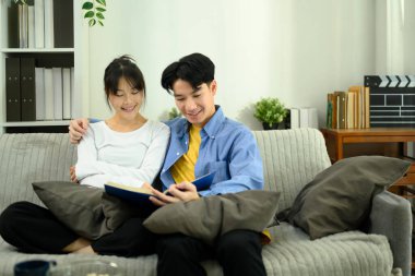 Mutlu genç çift kanepede oturup kitap okuyor..