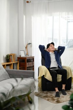 Rahat genç işadamı elleri başının arkasında rahat bir koltuğa yaslanıyor..