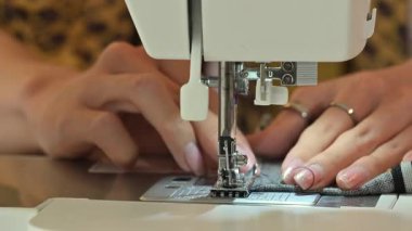 Yaratıcı bir çalışma alanında dikiş makinesi üzerinde çalışan genç tasarımcıyı kapat.
