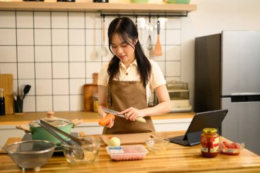 Güzel genç bayan, sıcak bir mutfakta spagetti için malzeme hazırlıyor..