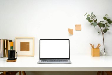 Boş ekranlı dizüstü bilgisayar, planlayıcı ve beyaz masa üzerinde beyaz kahve fincanı, minimalist ve modern çalışma alanı.