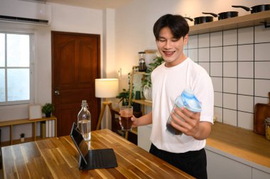 Spor kıyafetli genç adam idmandan sonra ahşap tezgahta protein içeceği hazırlıyor..