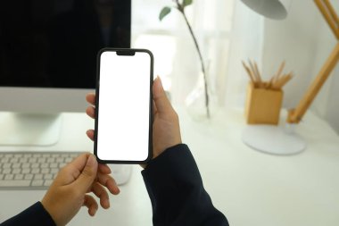 İş adamının elinde beyaz ekranlı akıllı telefon tutarak masasında oturmasını kapat..