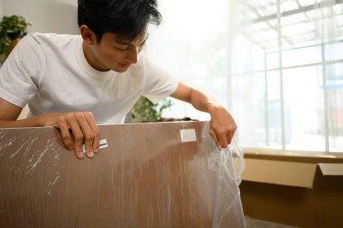 Mutlu Asyalı genç adam eşyalarını yerleştiriyor ve eşyalarını topluyor..