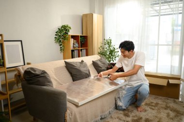 Mutlu Asyalı genç adam eşyalarını yerleştiriyor ve eşyalarını topluyor..