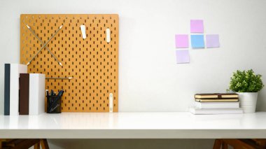 Tahtası, kitapları, yapışkan notları ve saksısı olan yaratıcı çalışma alanı.