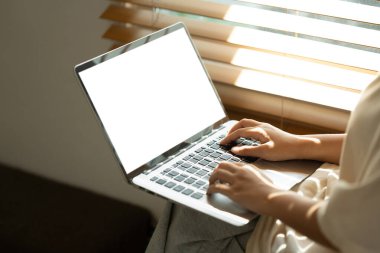 Dizüstü bilgisayarda boş beyaz ekranla yazan kadın ellerini kapat, pencerenin yanında oturuyor..