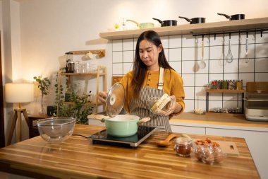 Modern bir mutfakta hazır erişte hazırlayan mutlu genç bir kadın..