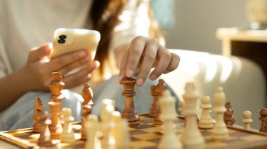 Akıllı telefon tutan ve klasik satranç tahtasındaki satranç taşını hareket ettiren kadın..