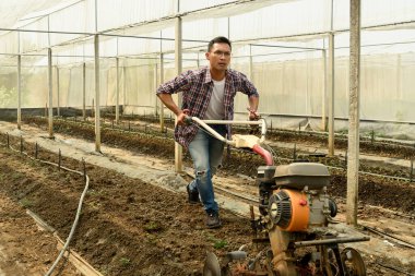 Bir serada tarla işçisi toprağı işliyor. Toprağı ekime hazırlıyor..