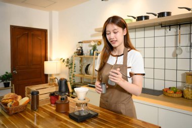 Önlüklü genç kadın sıcak bir ev mutfağında kahve hazırlıyor..