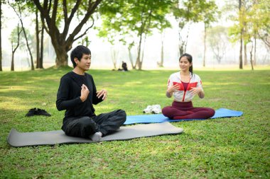 Genç çift huzurlu bir parkta nefes egzersizi yapıyor..