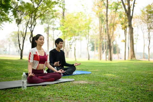 Erkek ve kadın parkta meditasyon yapıyorlar. Farkındalık ve zihinsel sağlık konsepti.