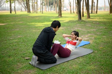 Mutlu genç çift yeşil bir parkta birlikte egzersiz yapıyor..