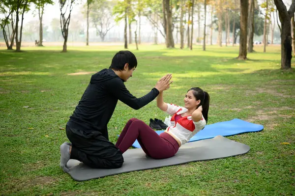 Mutlu genç çift yeşil bir parkta birlikte egzersiz yapıyor..