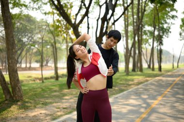 Genç bir adam ortağının koşmadan önce esnemesine ya da barışçıl bir yolda antrenman yapmasına yardım ediyor. Sağlıklı yaşam tarzı kavramı.