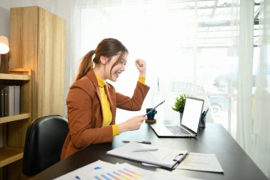 Heyecanlı iş kadını dijital tablette harika haberler okuyor. Parlak çalışma ortamında başarıyı kutluyor..