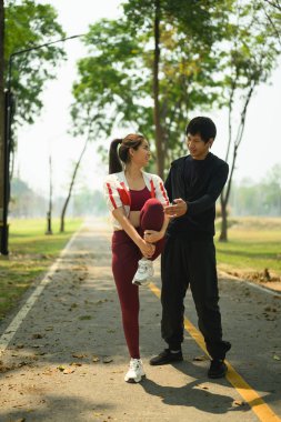 Genç bir adam ortağının koşmadan önce esnemesine ya da barışçıl bir yolda antrenman yapmasına yardım ediyor. Sağlıklı yaşam tarzı kavramı.