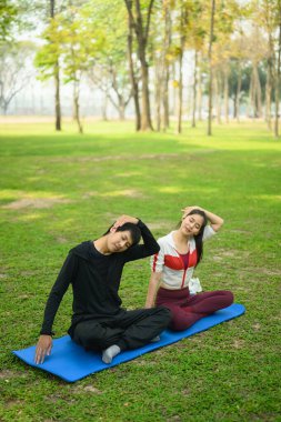 Atletik çift, huzurlu bir parkta egzersiz yaparken esneme hareketleri yapıyor. Sağlıklı yaşam tarzı kavramı.