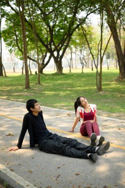 Yorgun bir adam ve kadın parkta oturmuş idmandan sonra dinleniyorlar..