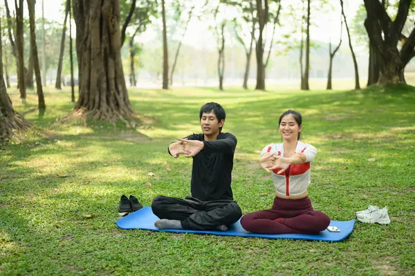Huzurlu bir parkta yoga minderleri üzerinde gerinen genç bir çift. Sağlıklı yaşam tarzı kavramı..