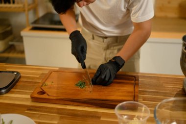 Mutfakta ev yapımı sarımsaklı tereyağı hazırlarken tahta kesme tahtasıyla maydanoz doğrayan adama yaklaş..