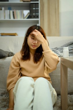 Elleri alnında yerde oturan genç bir kadın. Sağlık, sağlık veya zihinsel yorgunluk kavramları.