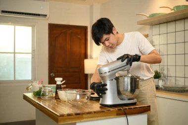 Genç adam elektrikli tezgahta çırpılmış krema hazırlamak için mikser kullanıyor..