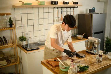 Asyalı adam ev mutfağında krem şanti için malzeme hazırlıyor..