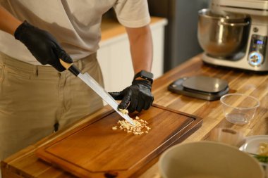 Modern bir mutfağın tahta kesme tahtasıyla sarımsak doğrayan adama yakın çekim..