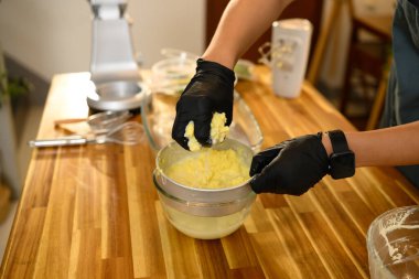 Sıcak bir mutfakta taze tereyağı elde etmek için tereyağı sıkan bir adam..