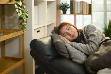 Genç Asyalı kadın yastıkla rahat koltukta uyuyor..