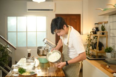 Odaklanmış Asyalı adam sıcak bir mutfakta taze tatlı malzemesi yapıyor..