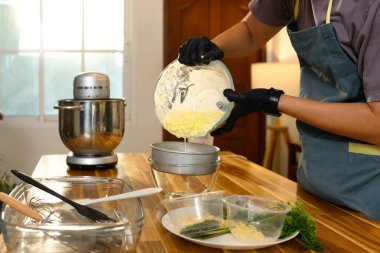 Eldiven ve önlük giyen aşçılık meraklısı ev yapımı tereyağı hazırlıyor..