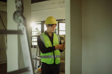 Sarı şapkalı elektrikçi inşaat alanındaki elektrik tesisatında çalışıyor..