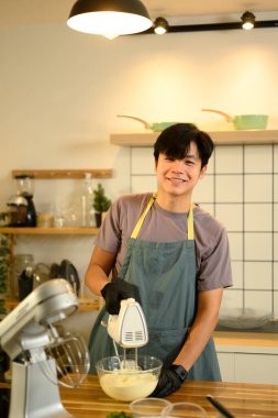 Siyah eldivenli adam cam kasede kremayla elektrikli el mikserini karıştırıyor..