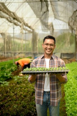 Elinde bir tepsi sebze tohumu tutan gülümseyen adam. Sürdürülebilir tarım kavramı.