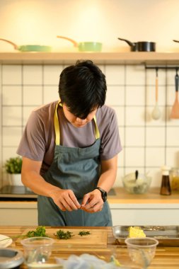 Genç adam ev yapımı sarımsaklı tereyağı yapmak için malzeme hazırlıyor..