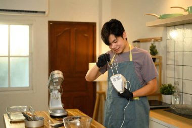 Gülümseyen adam tereyağı yapmak için el çırpıcı hazırlıyor..