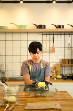 Genç adam mutfakta yeni yapılmış tereyağını elle şekillendiriyor..