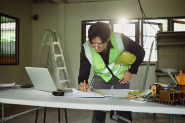 Tadilat alanındaki inşaat planlarını inceleyen mühendis..