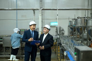 Modern bir imalat tesisinde güvenlik miğferleri denetleyicileri süreçleri gözden geçiriyorlar.