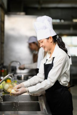 Yemek kursunda sebze yıkayan kız öğrenci.