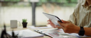 Dijital tablet kullanan ve raporları inceleyen bir işadamı.